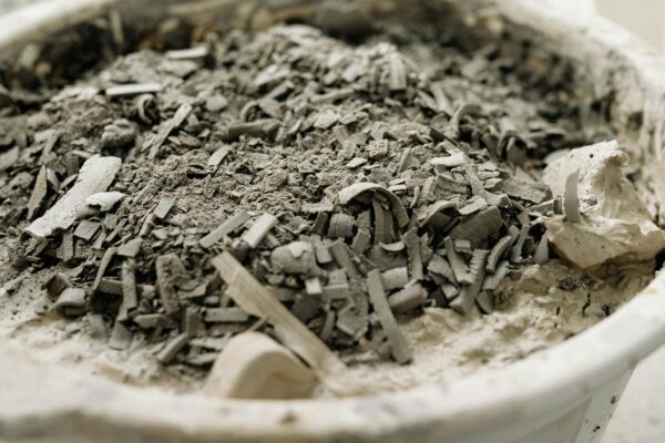 Detailed close-up of a white bowl filled with ashes and debris, highlighting texture.